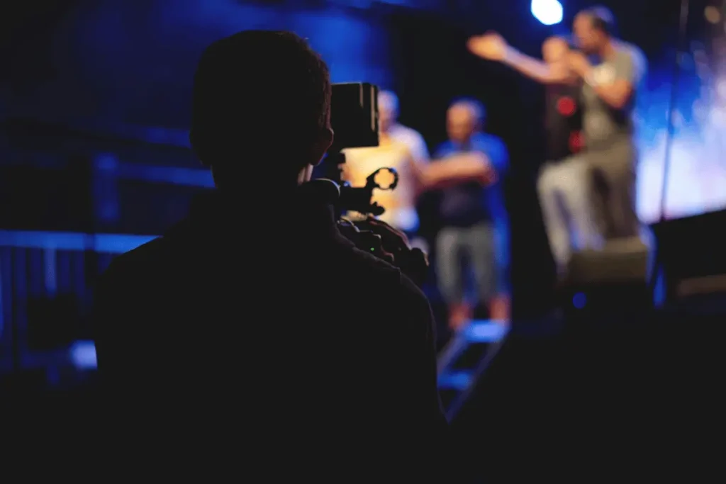 Silhouette of a cameraman filming a performance on stage.