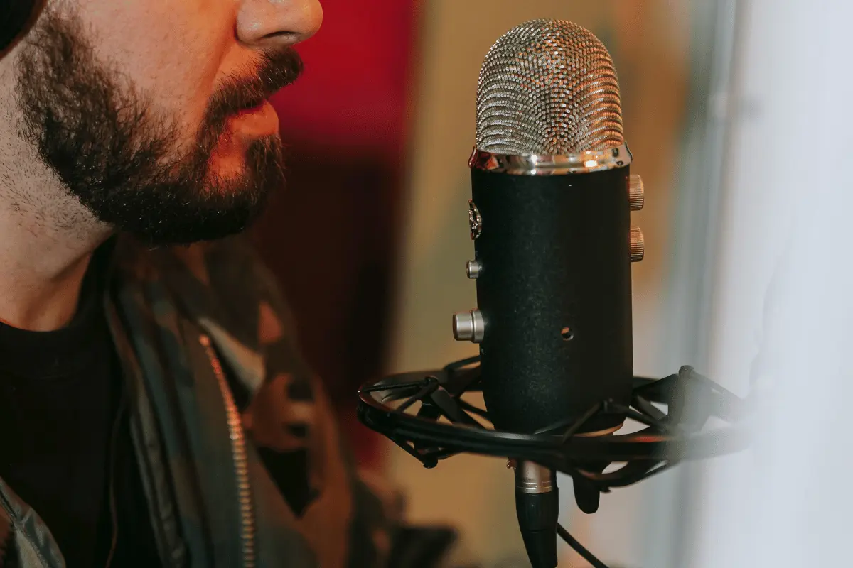 Close-up of a bearded man speaking into a professional studio microphone.