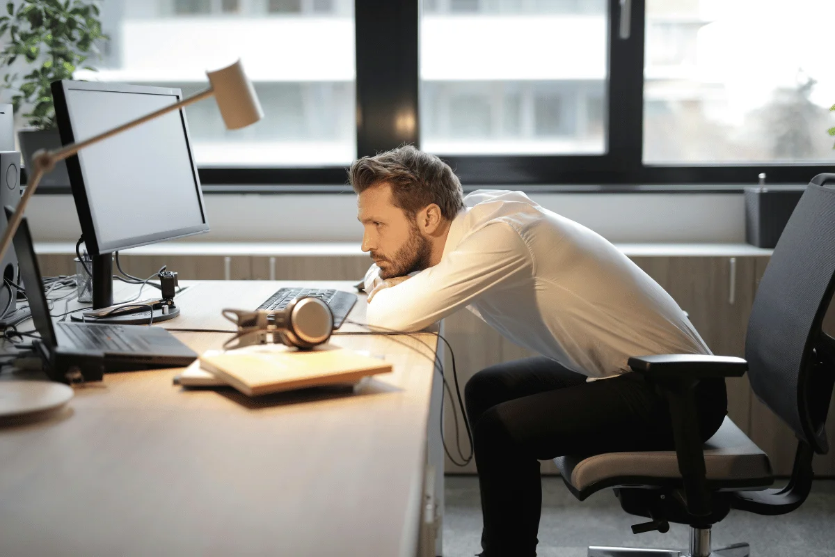 Concentrated man reviewing content on computer with microphone on desk.