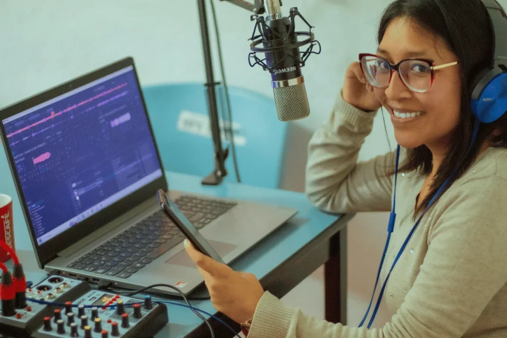 Content creator with glasses and headphones works on a podcast at her desk.