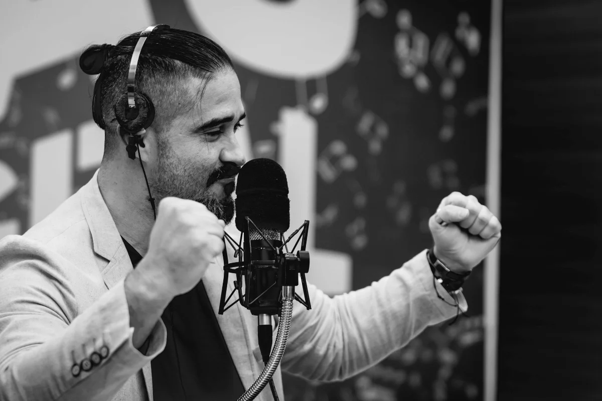 Engaged man in headphones, speaking into a microphone in a studio, illustrating a professional podcast or radio show setup.