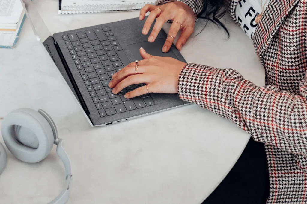 Professional setting with a woman working on a laptop, style in focus.