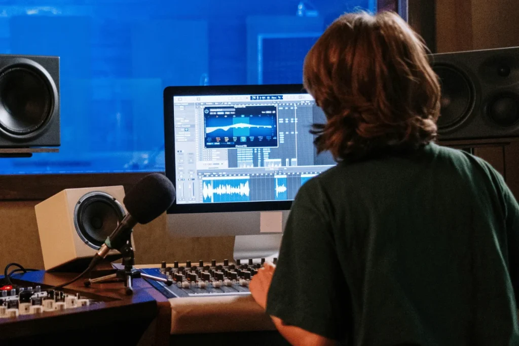 Audio engineer editing sound on desktop in studio.