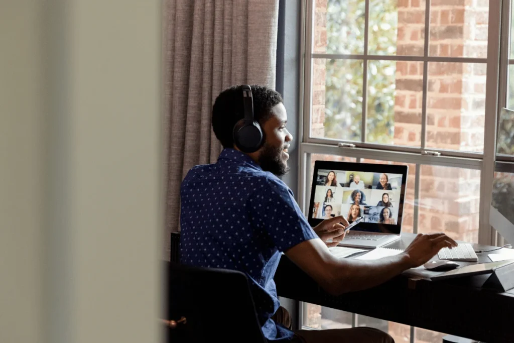 Man wearing headphones participating in a virtual meeting by his window.