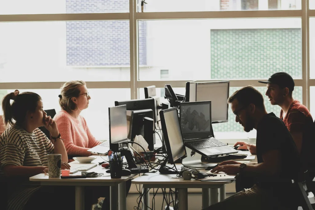 People working at computers in a bright office environment.