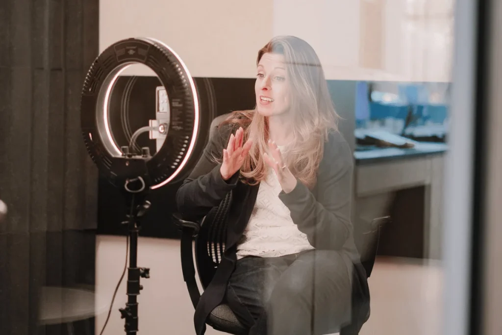 Woman speaking during a podcast recording session with ring light.