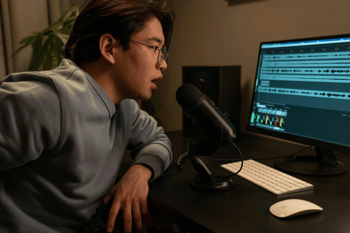 Person speaking into a microphone while monitoring audio levels on a screen.