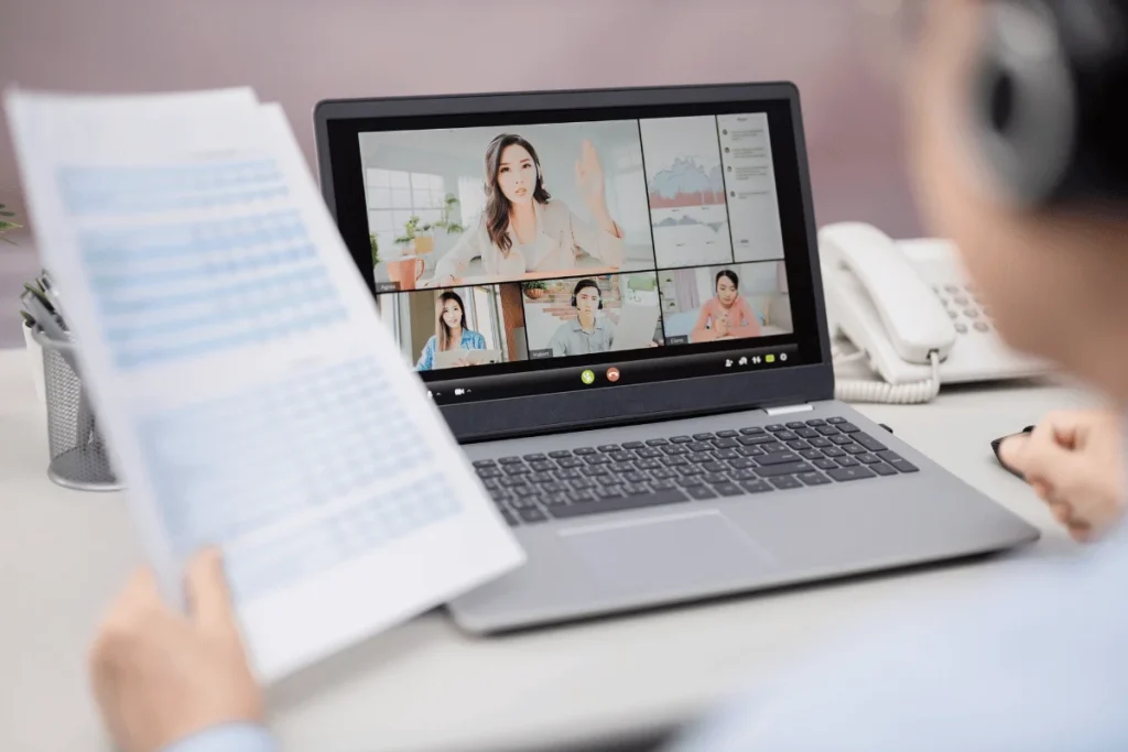 Person in a headset analyzing data during a video conference on a laptop.