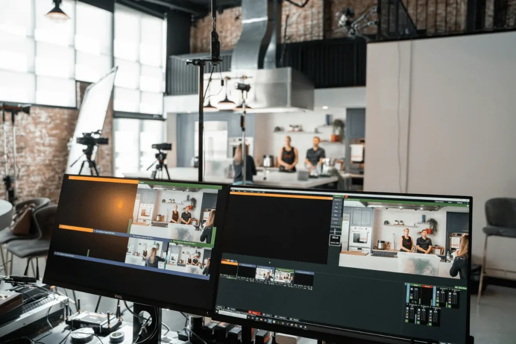 Video production setup with multiple cameras and monitors showing a kitchen studio shoot.