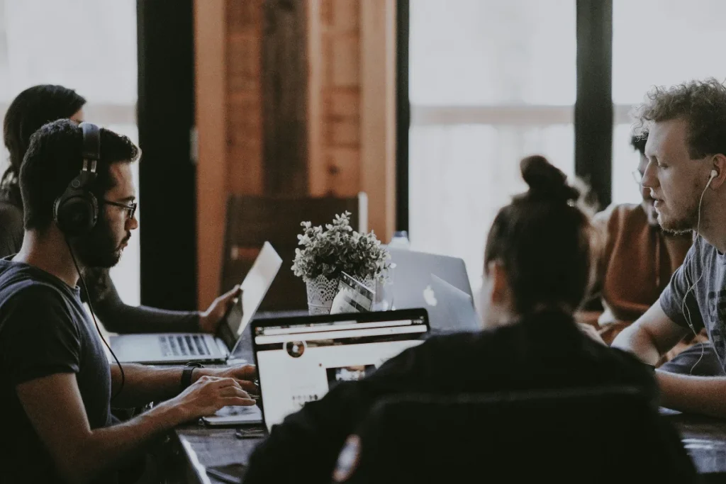 Group of people working on laptops in a collaborative workspace.