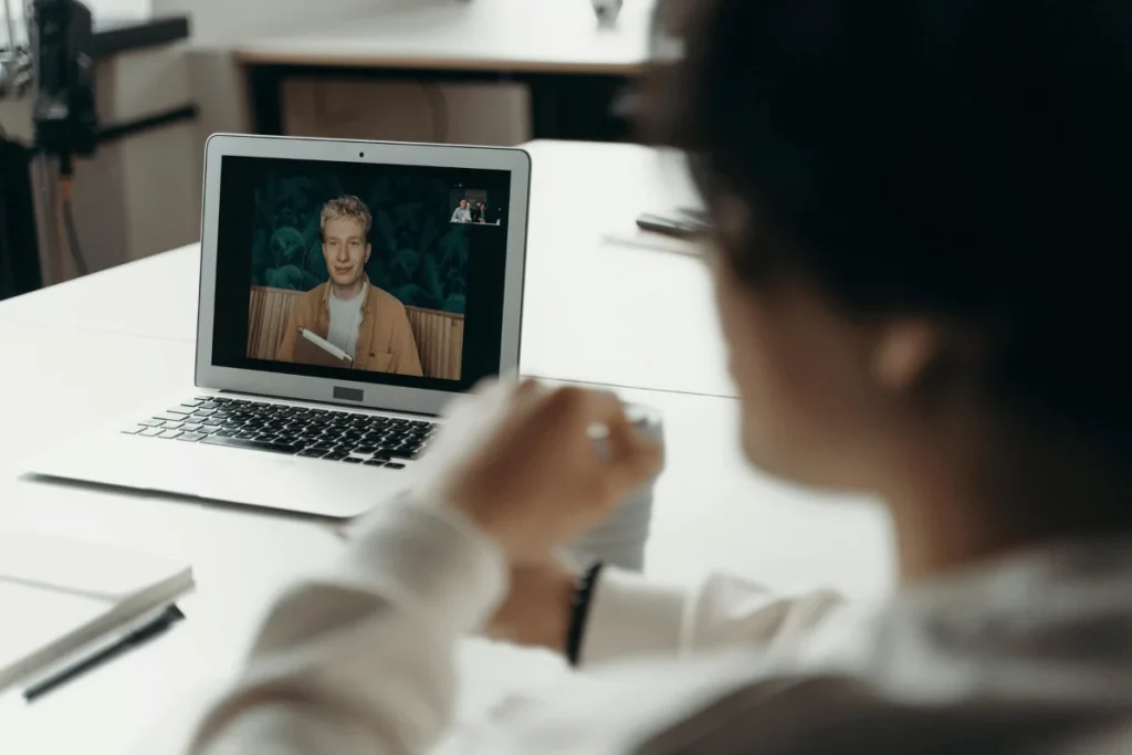 Person in a white shirt having a video call on a laptop.