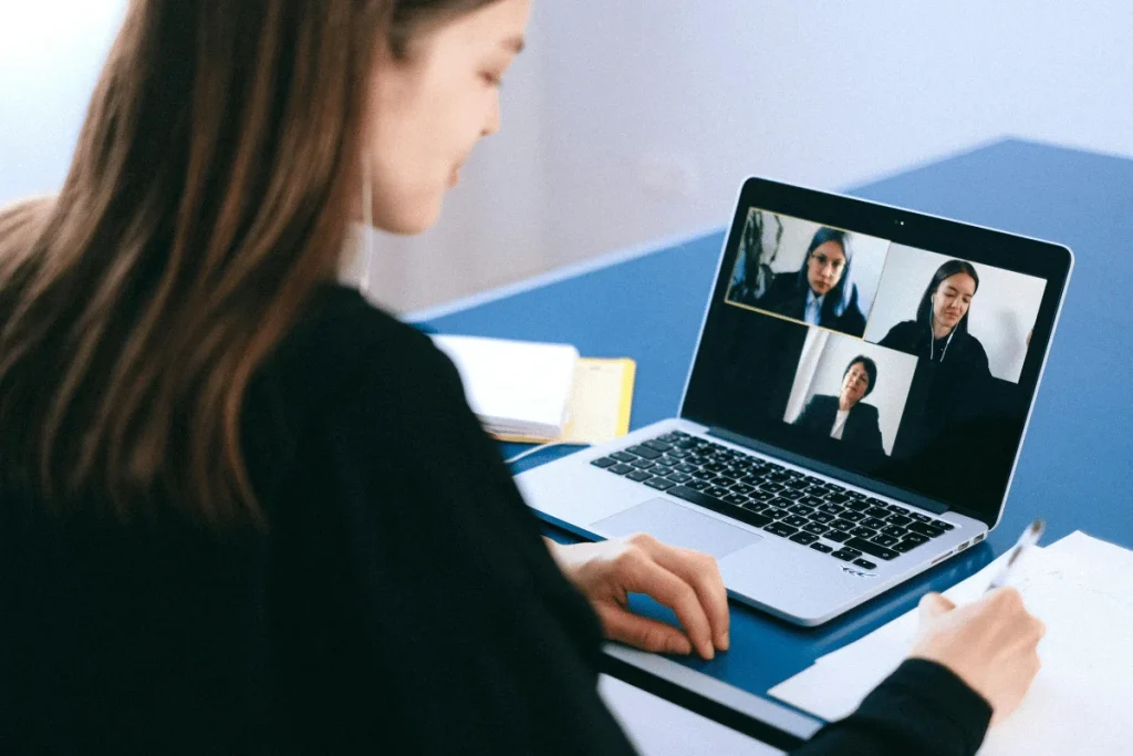 Woman in a video call meeting with three people on laptop screen.