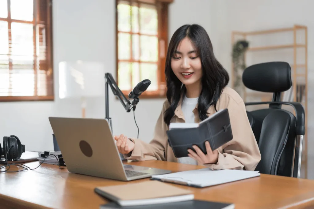 Female podcaster recording a show with a microphone and laptop.