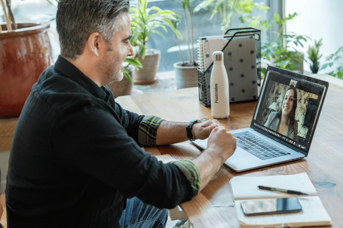 A man having a virtual meeting on a laptop with a female colleague.