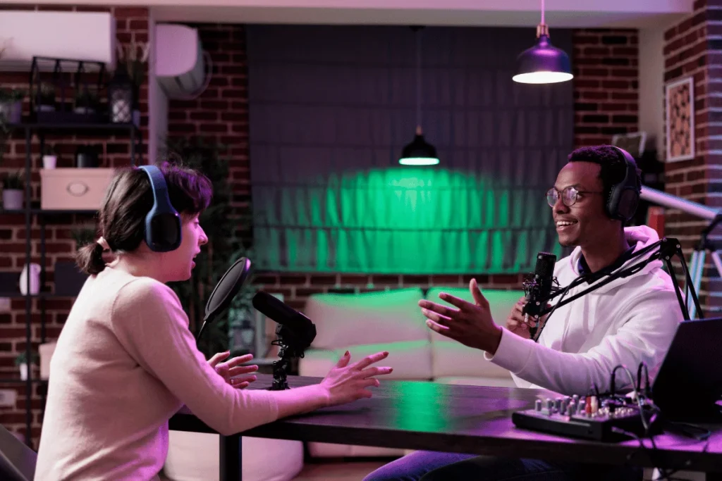 Two podcasters recording an episode with microphones and headphones.