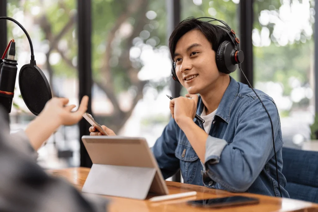 Close-up of a person taking notes while recording a podcast with a microphone.