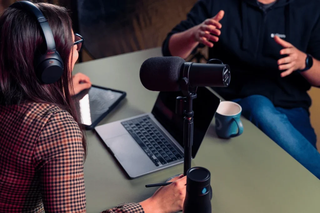 Podcast interview setup with a female host wearing headphones and a guest speaking.
