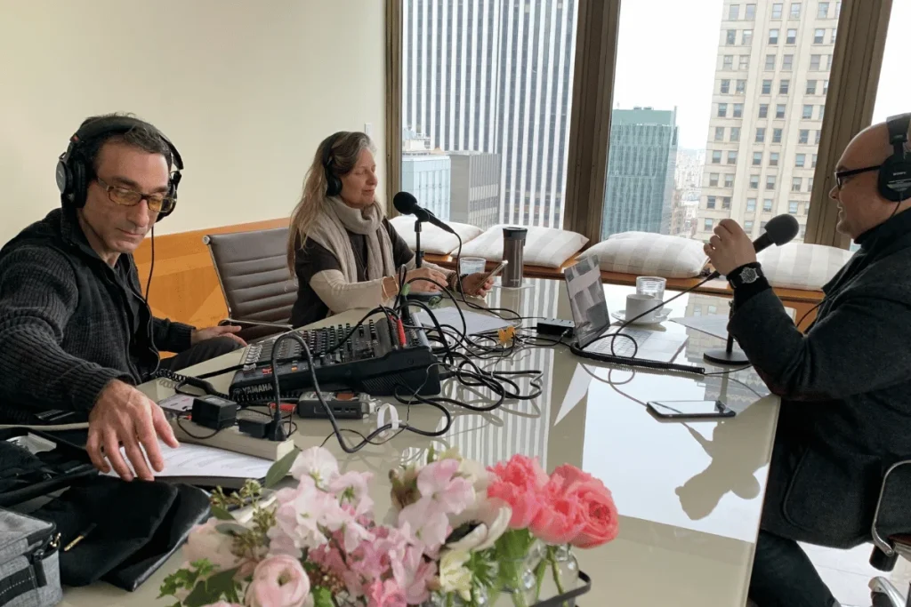 Podcast recording session with three people wearing headphones and speaking into microphones.