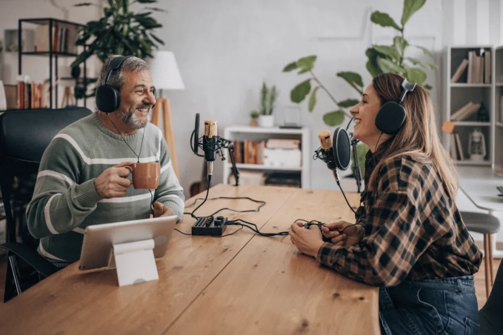 Two cheerful podcasters recording in a soundproof studio with a high-quality microphone setup.