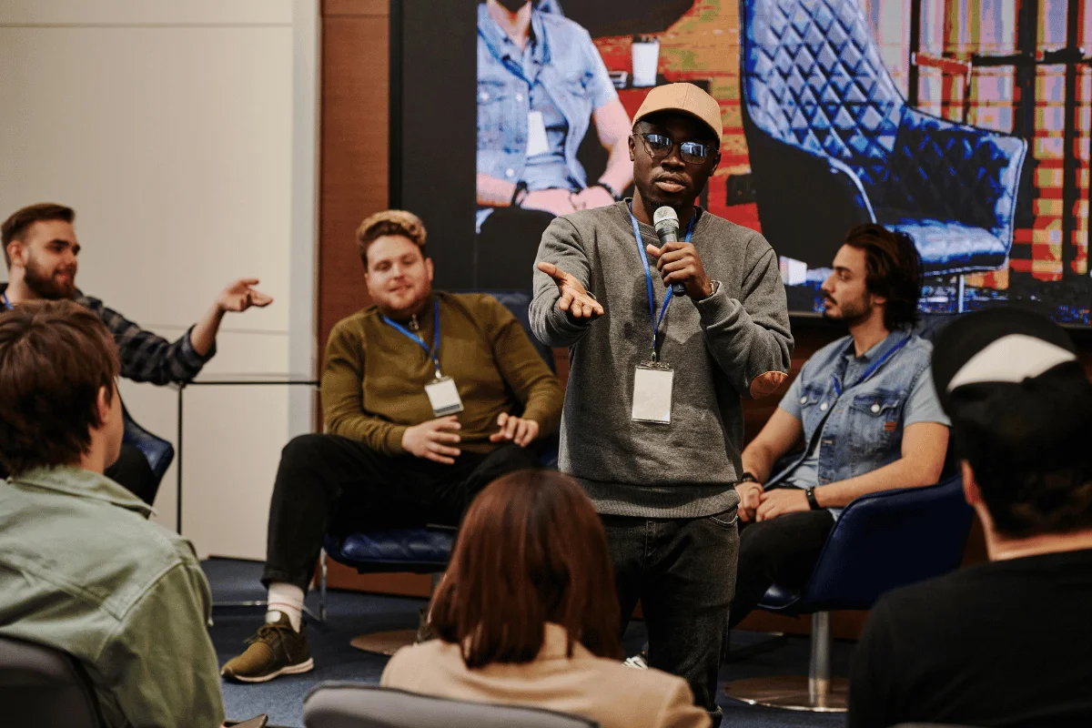 Man speaking into a microphone at a panel discussion event. Speaker addressing an audience during a conference Q&A ses