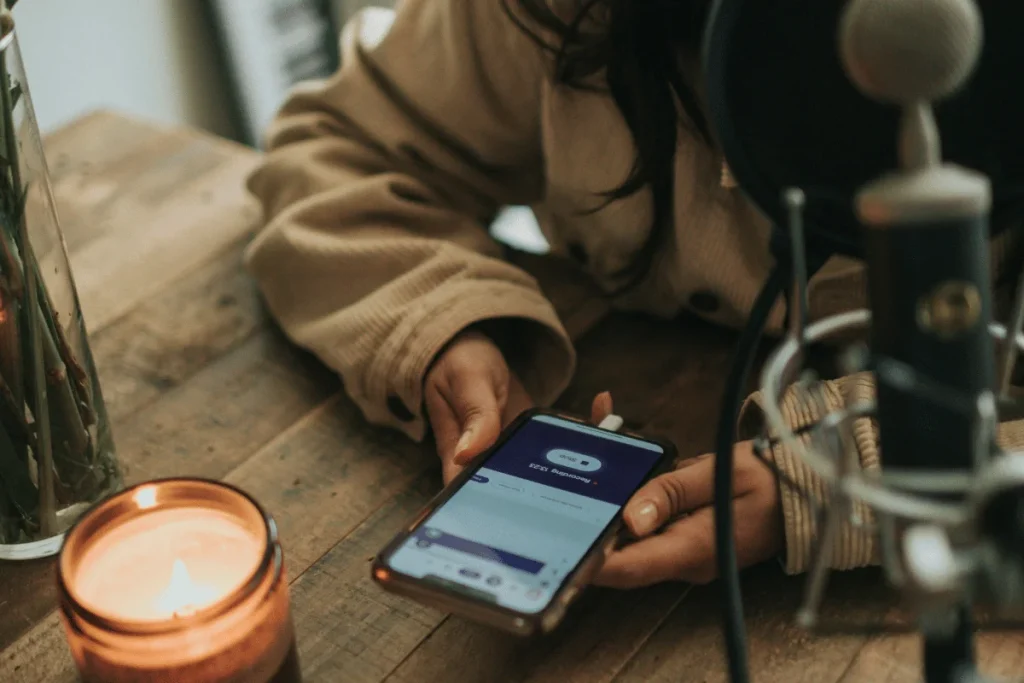 Close-up of a podcast recording setup with a mobile phone and professional microphone.
