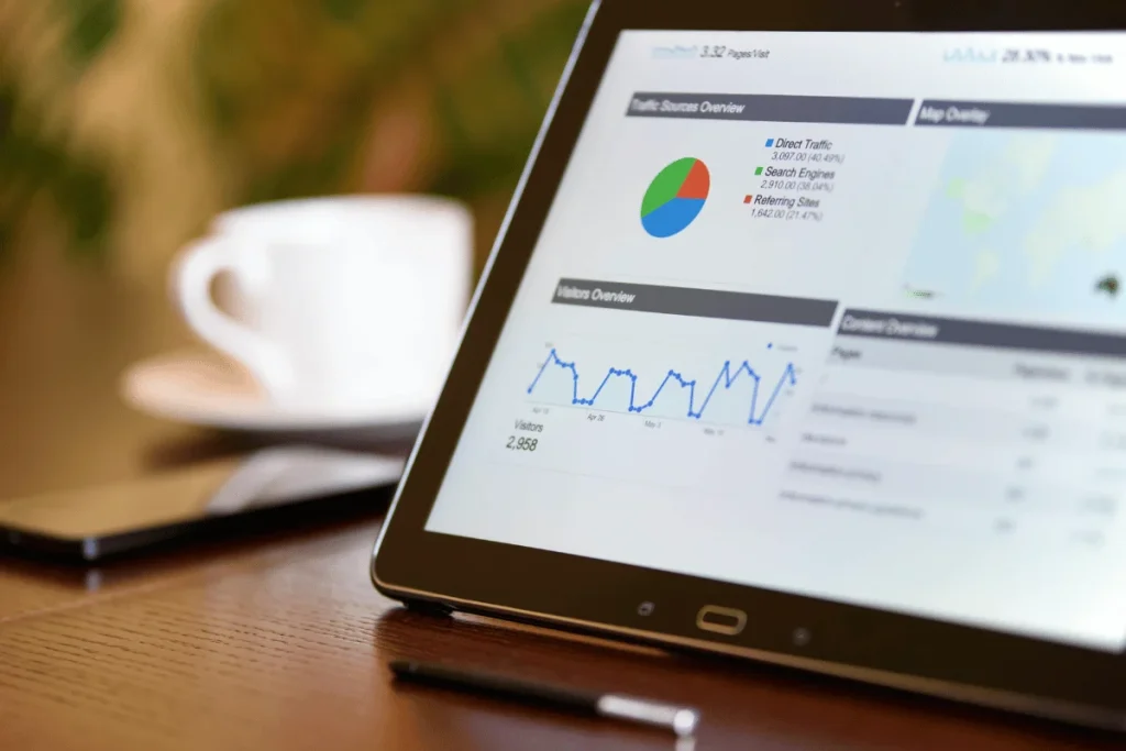 A tablet showing website traffic data with a cup of coffee and smartphone in the background.