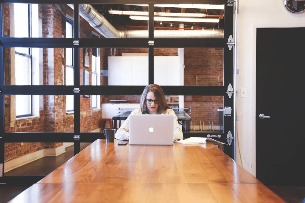 Stylish workspace featuring a diligent worker on an Apple laptop amid brick decor.