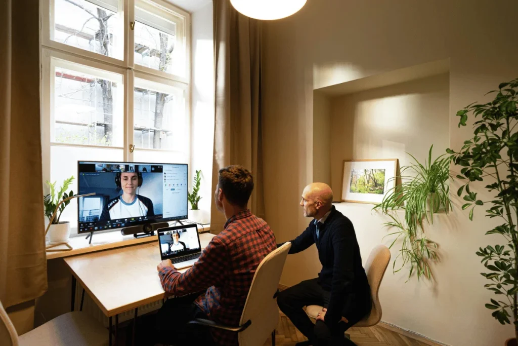 Two men in a home office on a Zoom video call with colleague.