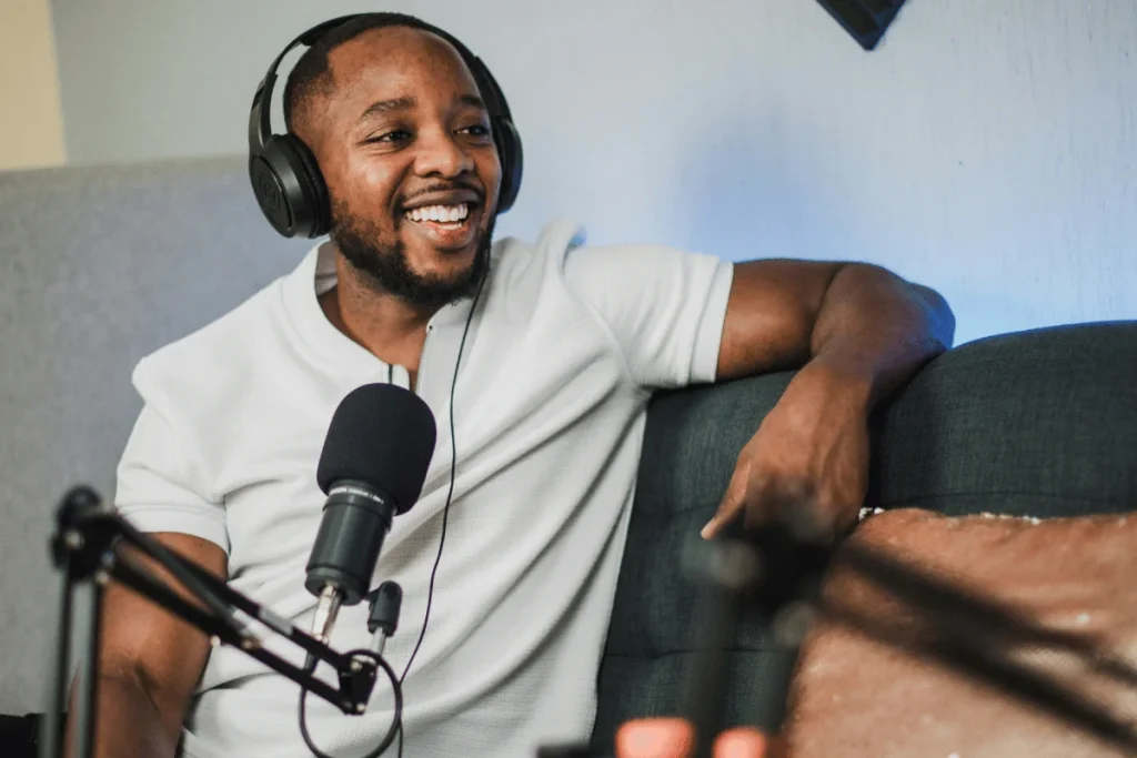 Man smiling while recording a podcast with a professional microphone and headphones.