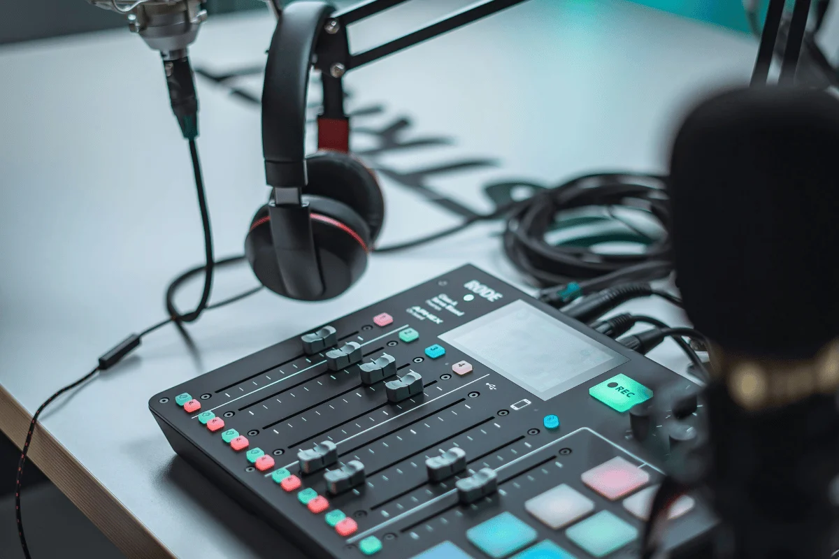 Podcasting setup with a mixer, microphone, and headphones on a table. The image conveys a professional and creative atmosphere.