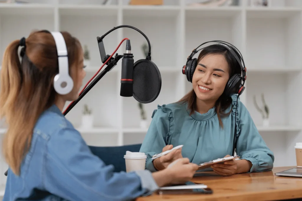 Female podcasters discussing topics with a professional microphone setup.