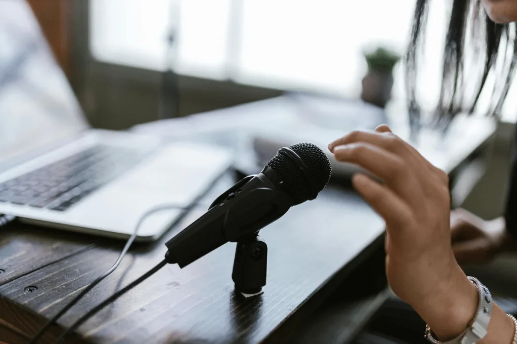Podcaster setting up a microphone on a desk with a laptop nearby.