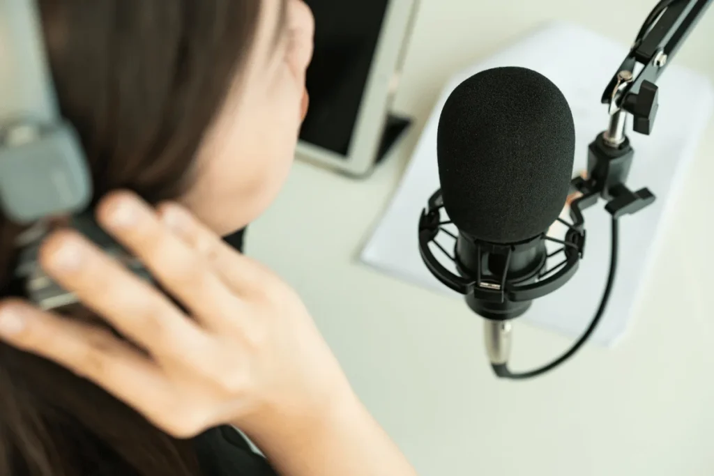 Close-up of a person with headphones speaking into a professional microphone.