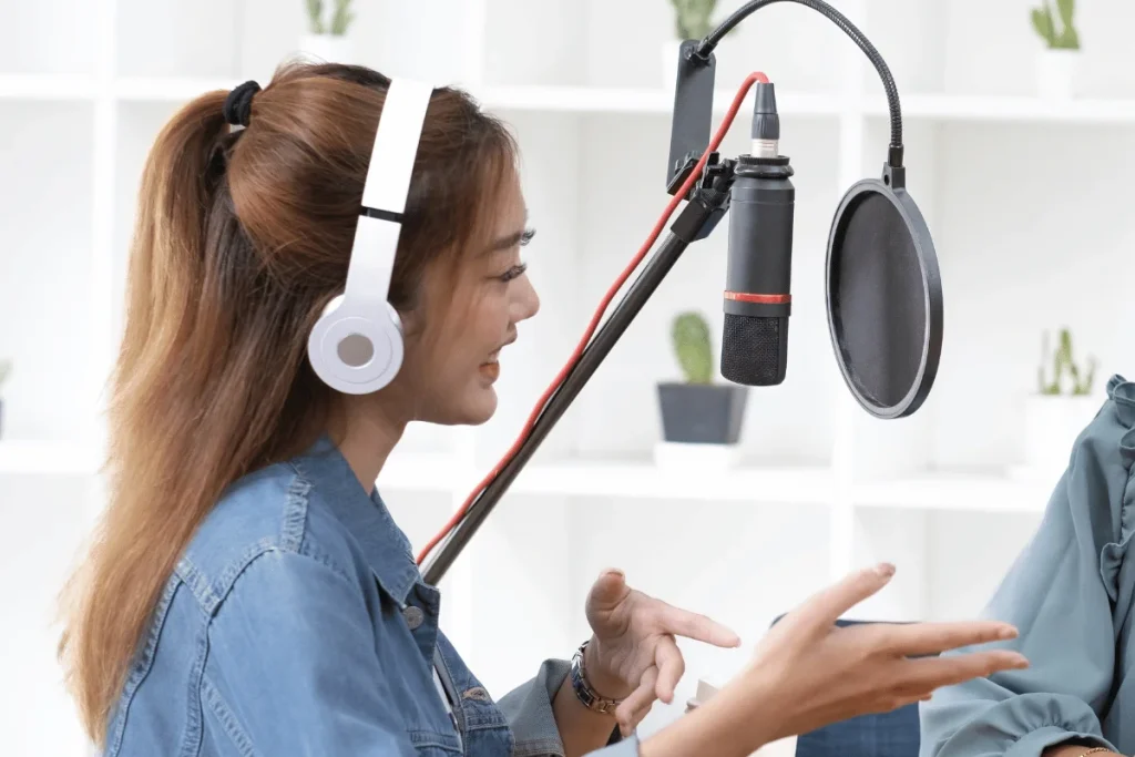 Woman wearing headphones recording podcast with professional microphone.