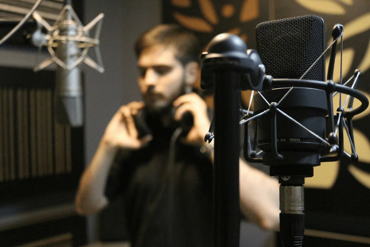 Professional studio microphone with a blurred podcaster in the background.