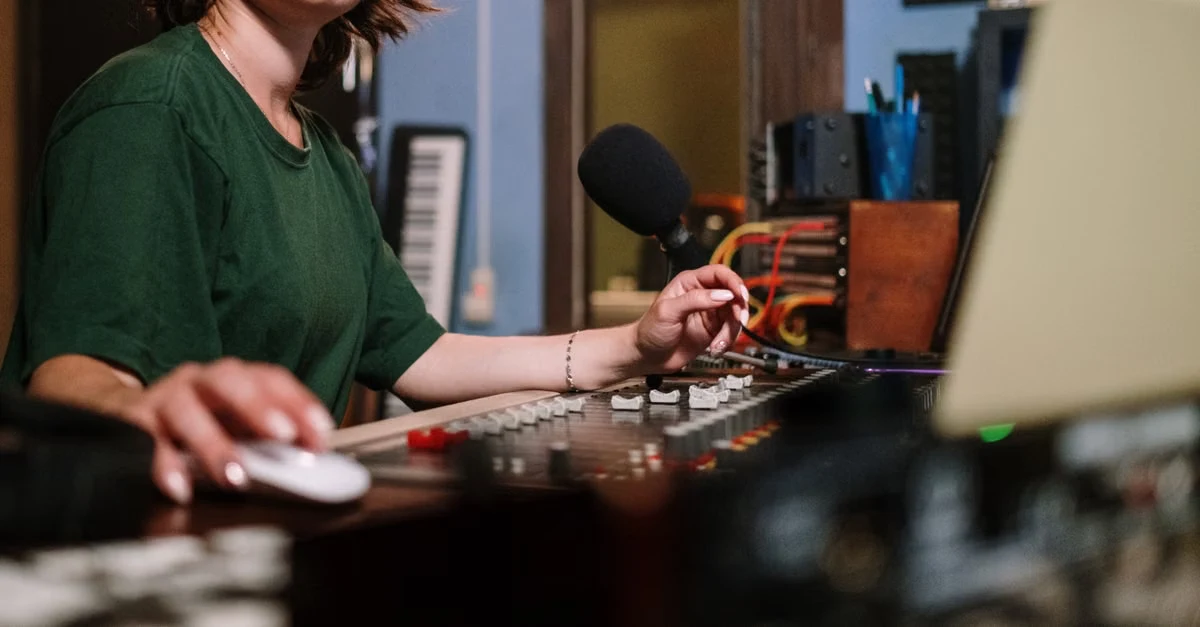 Woman recording podcast at desk with microphone, mixer, and laptop for community platforms content creation.