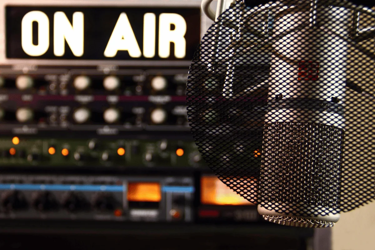 Close-up of a professional microphone with a "ON AIR" sign in the background during a live recording session in a studio.