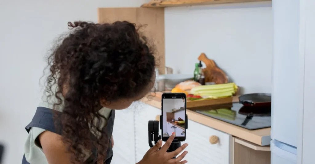 Woman recording kitchen content on smartphone mounted on tripod to repurpose TikTok videos across social platforms.