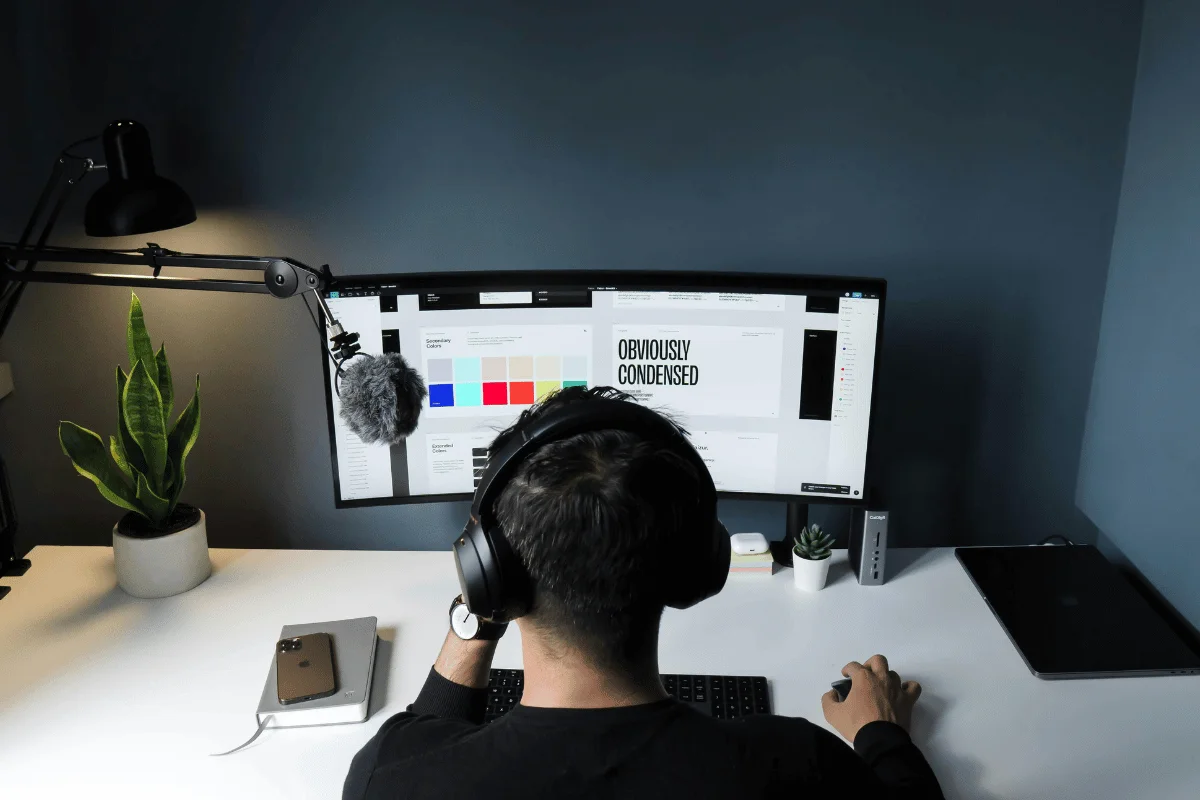 Content creator with over-ear headphones edits digital art in a stylish office.