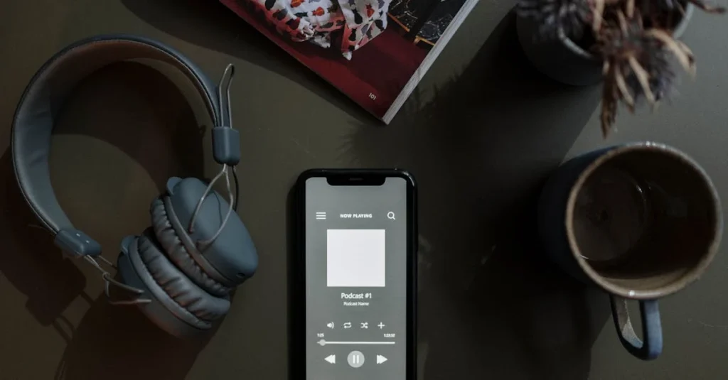 Smartphone displaying personalized podcast feeds interface with headphones and coffee cup on dark desk.