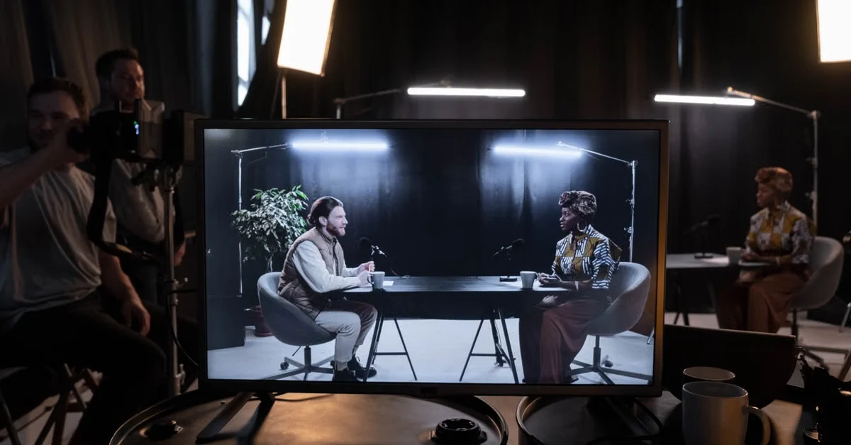 Professional podcast studio setup showing two hosts during live interview recording with professional lighting equipment.
