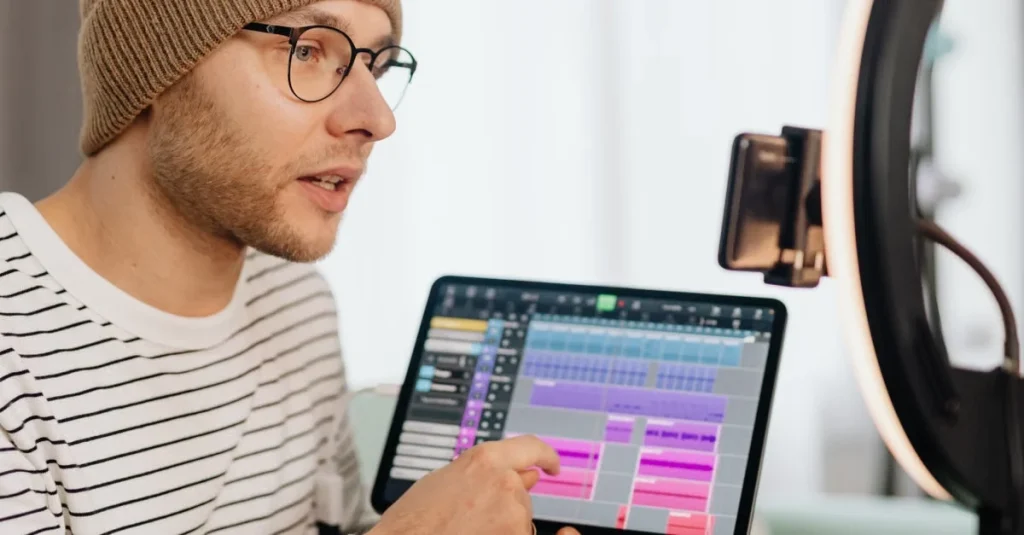 Male podcaster editing audio tracks on tablet with ring light setup for podcast hosting comparison guide.