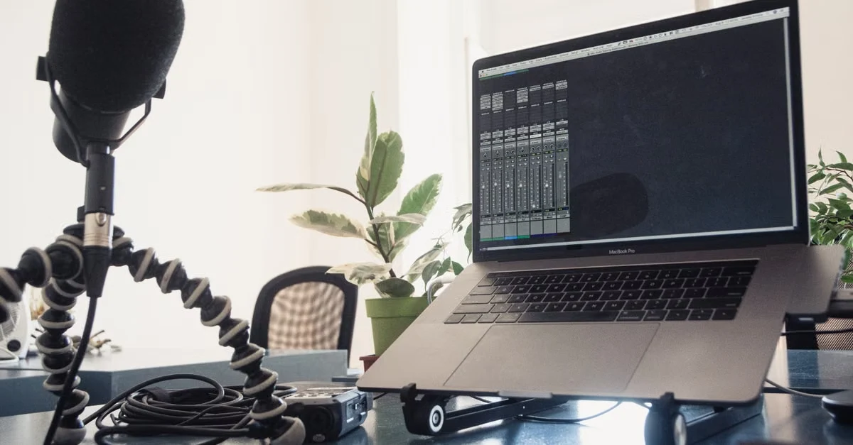 Podcast studio setup with microphone, laptop displaying audio interface, and plants for private podcast production.